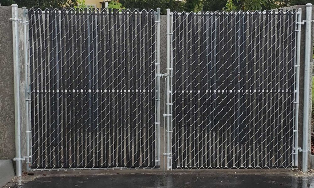 chain link gate with privacy slats mounted to a dumpster enclosure